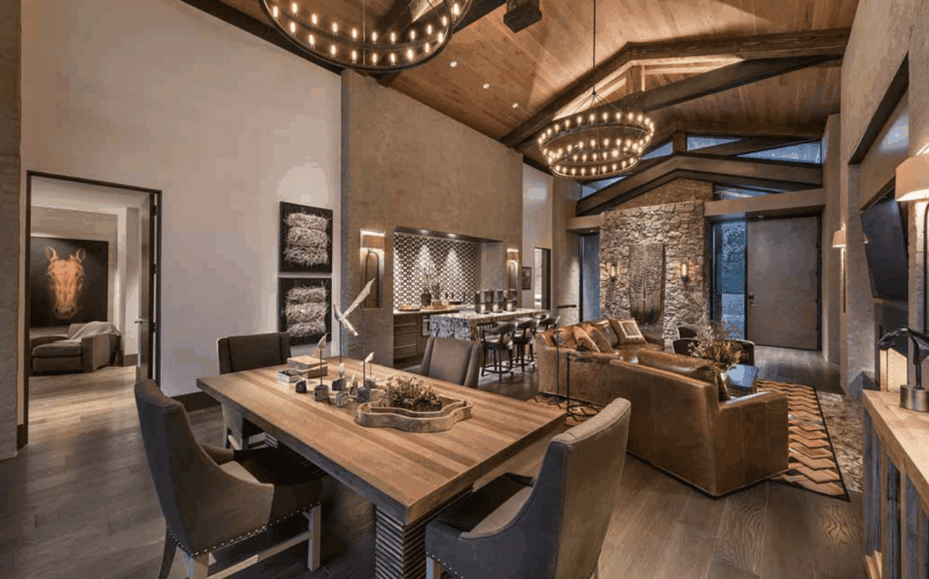 Rustic dining room with wood-beamed ceilings and stone fireplace.